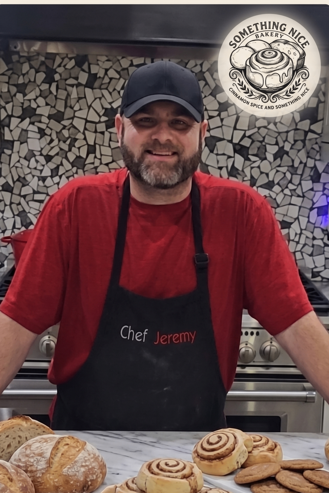 Chef Jeremy in the kitchen with fresh cinnamon rolls, bread, and cookies